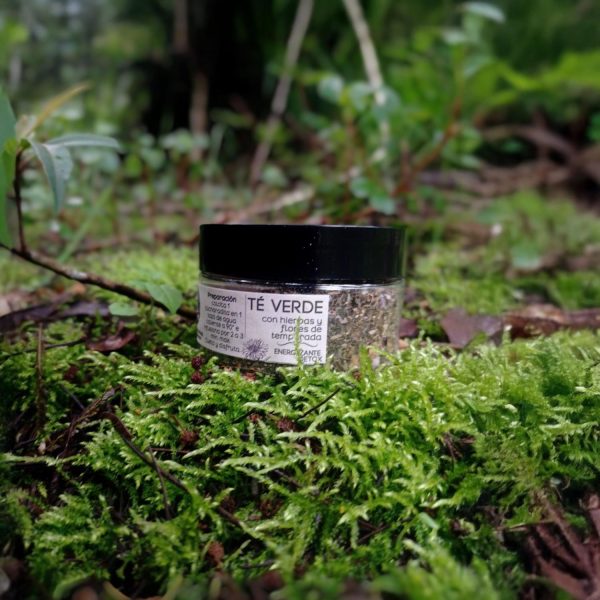 Frasco pequeño de té verde con etiqueta visible en bosque sobre musgo